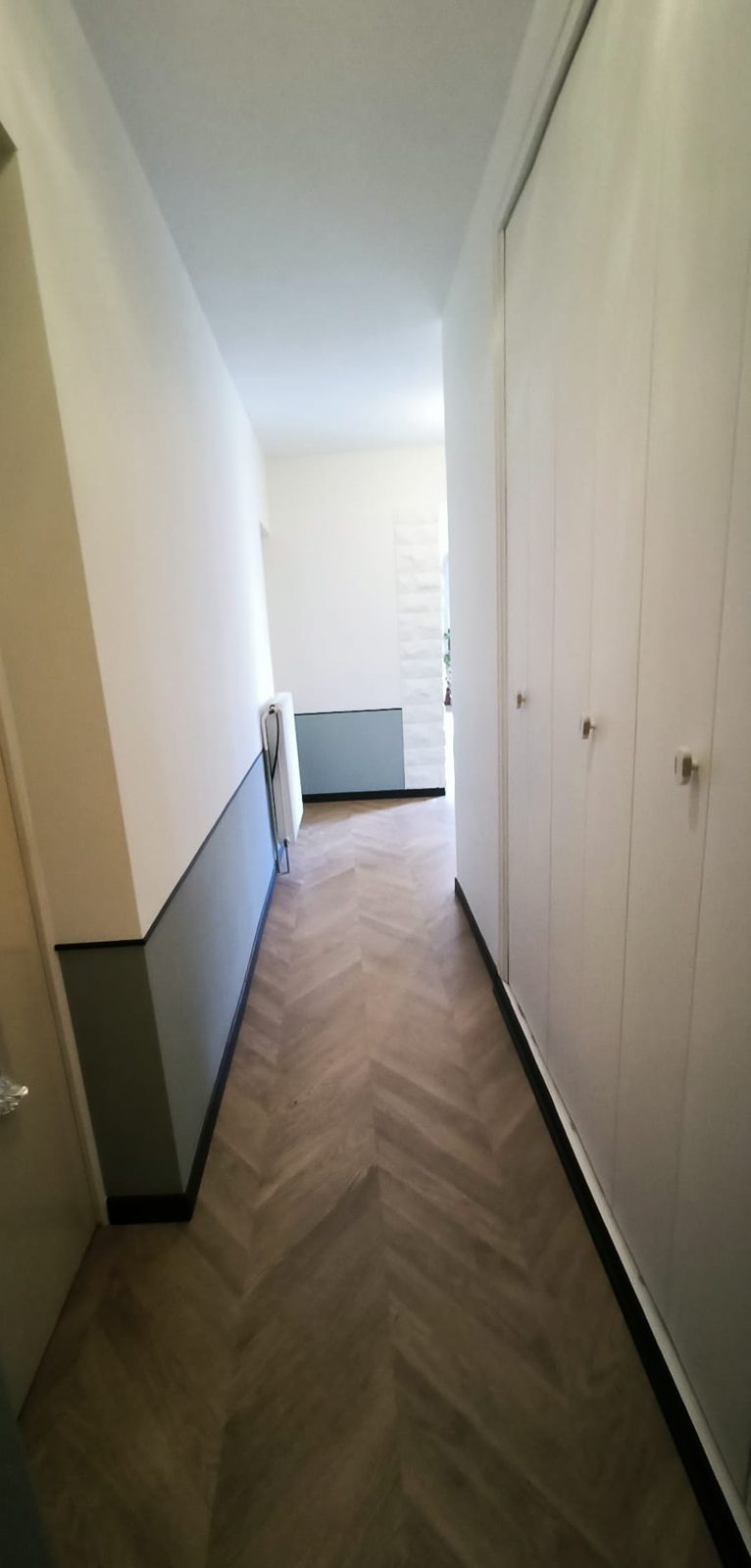 Après travaux : couloir avec sol posé en chevron et soubassement peint en vert de gris
