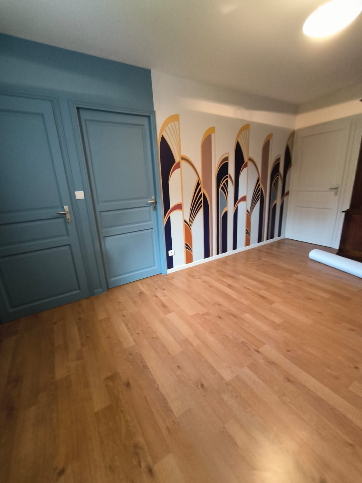 Chambre aux portes bleues avec un mur décoré d'arches Art déco peintes en bleu, doré et beige