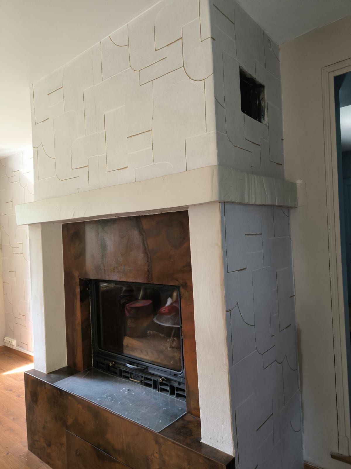 Cheminée habillée d'un décor géométrique en relief, ton sur ton