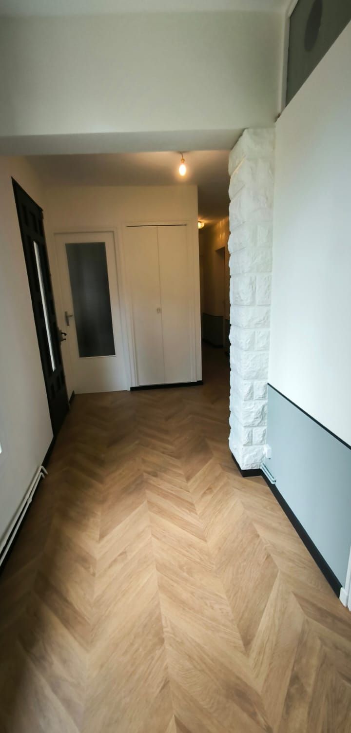 Couloir avec un sol posé en chevron et un soubassement peint en vert