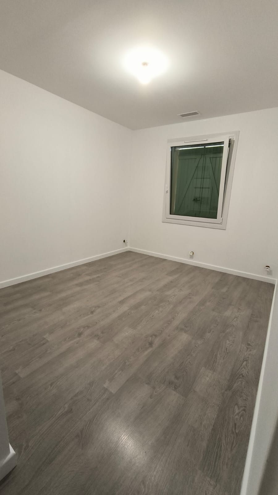Chambre aux murs blancs avec un sol en lames grises