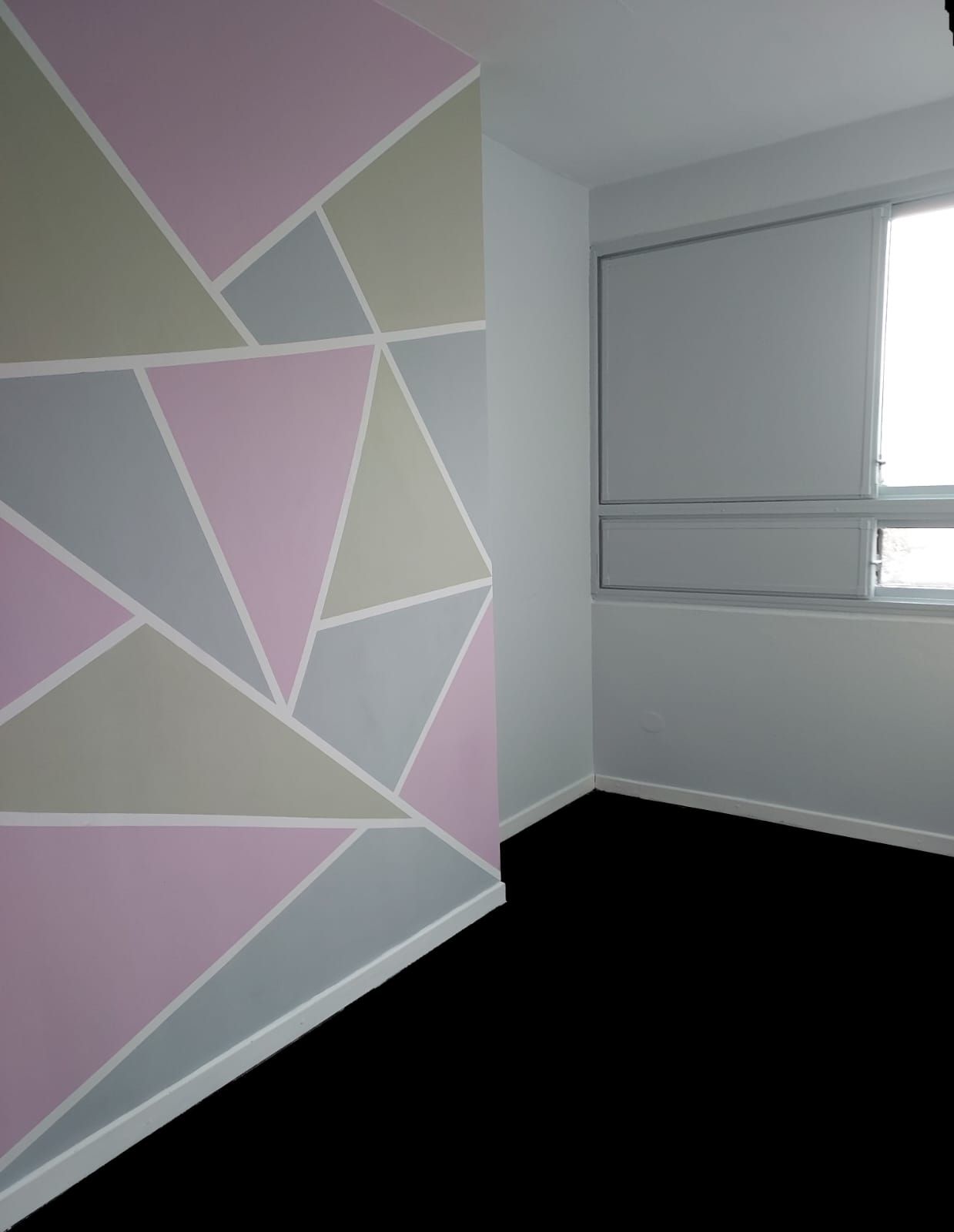 Mur peint de triangles rose, gris et vert pâle séparés par des filets blancs